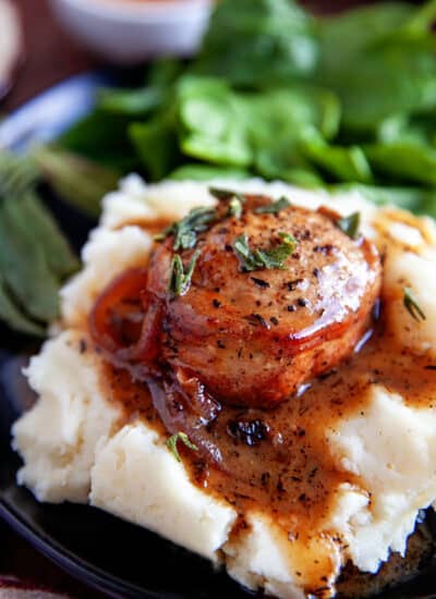 Bacon-Wrapped Pork Tenderloin on mashed potatoes with a gravy.