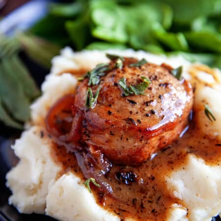 Bacon-Wrapped Pork Tenderloin on mashed potatoes with a gravy.