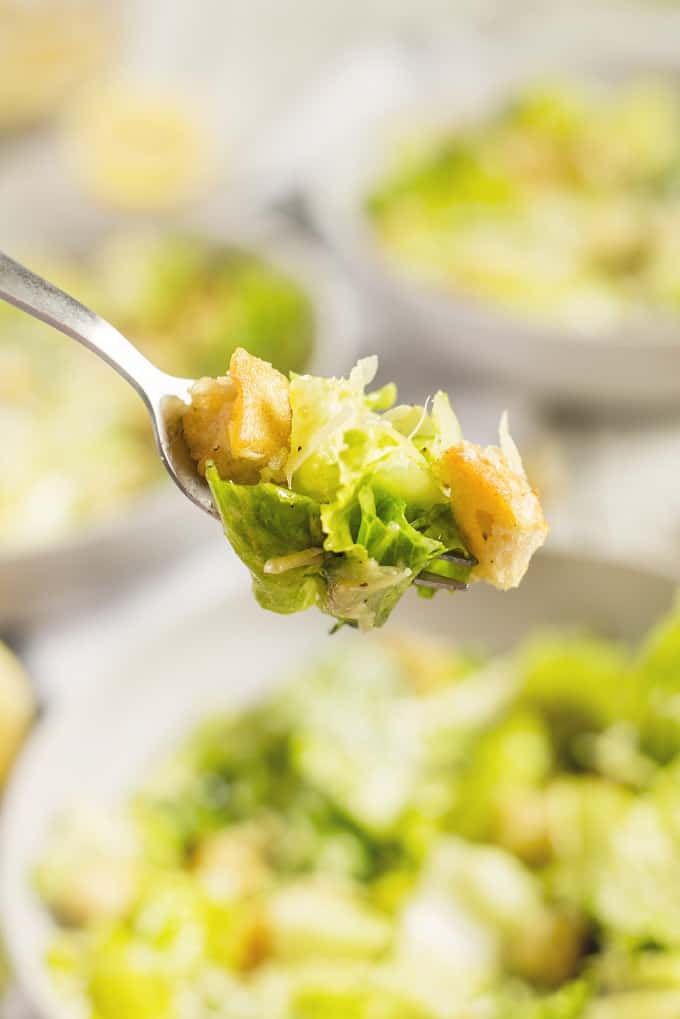 Closeup of a fork with a bite of Caesar salad on it