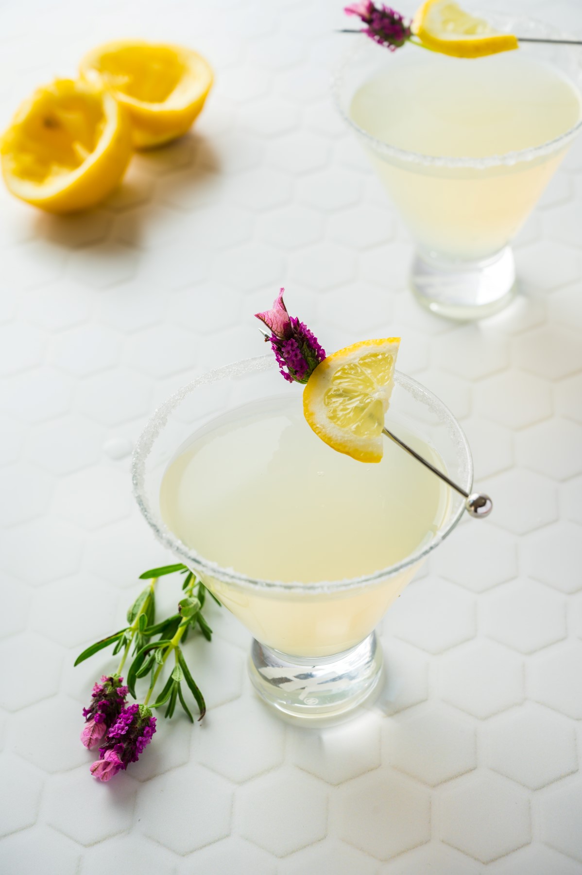 Shot of two martinis with squeezed lemons and flowers. 