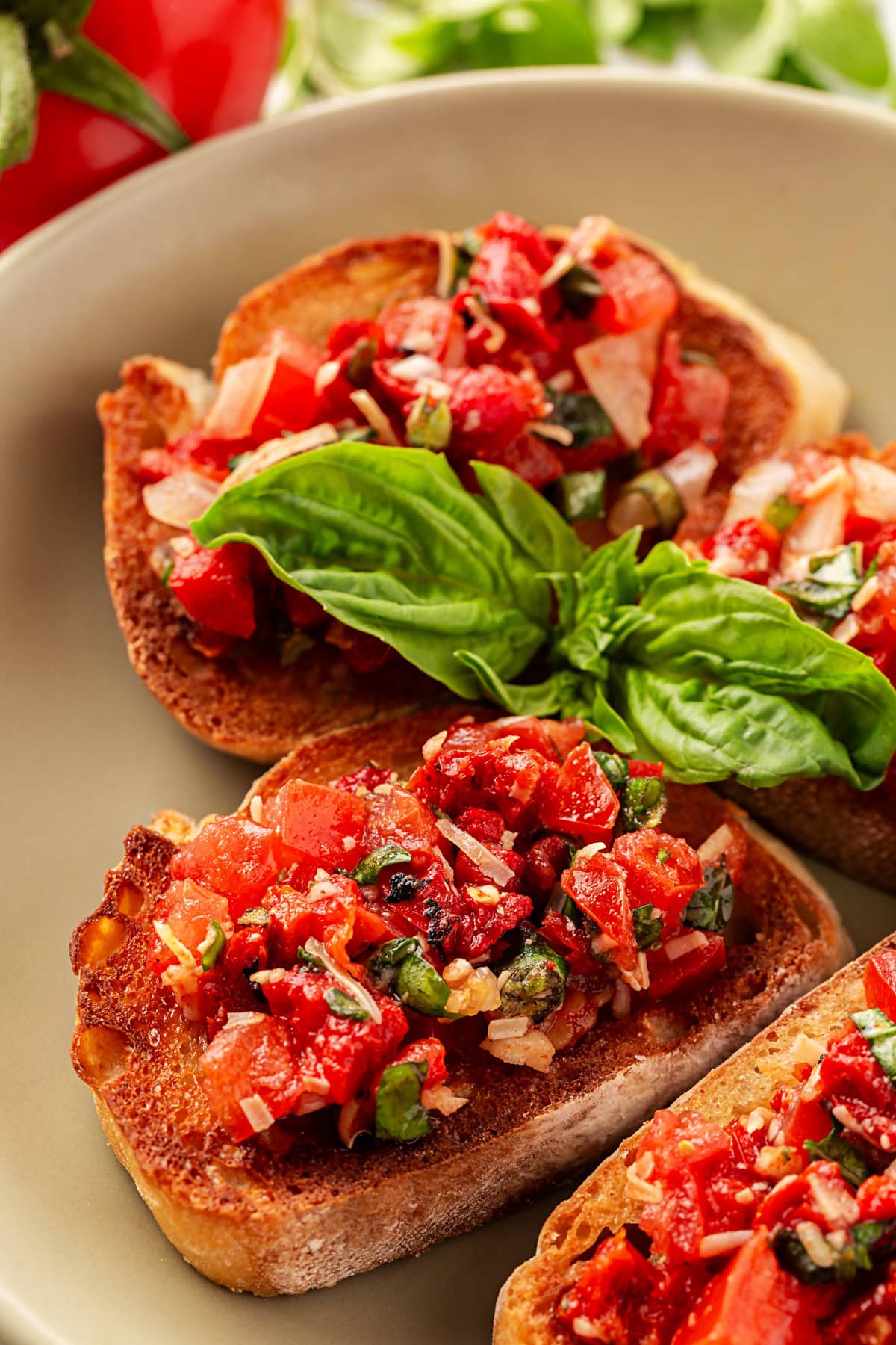 This Best Tomato Bruschetta recipe will have you making it all year round. The flavors are perfectly balanced and one that I get rave reviews from. Bruschetta served with a fresh basil leaf.