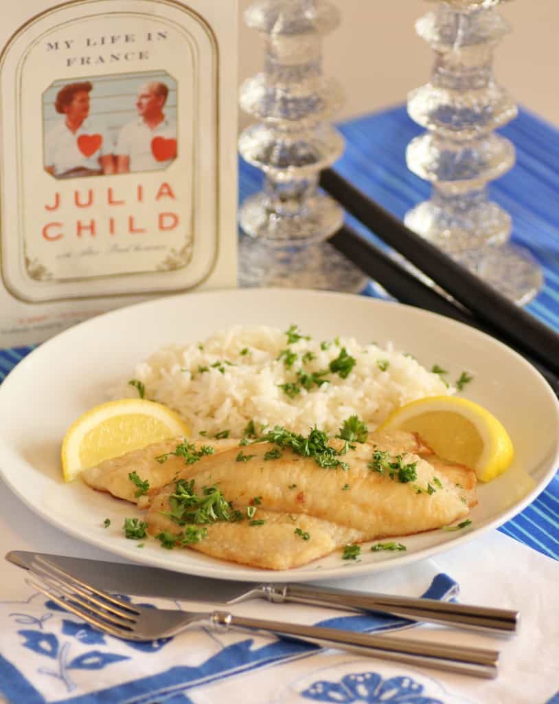 Fillets of Sole Meuniere on a white plate with rice garnished with parsley and lemon wedges