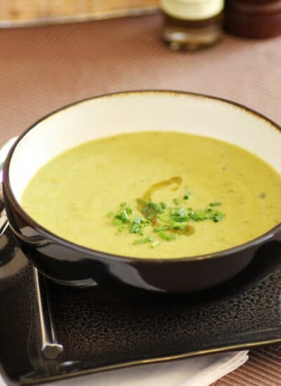 Asparagus Soup in a black bowl with chives on top.