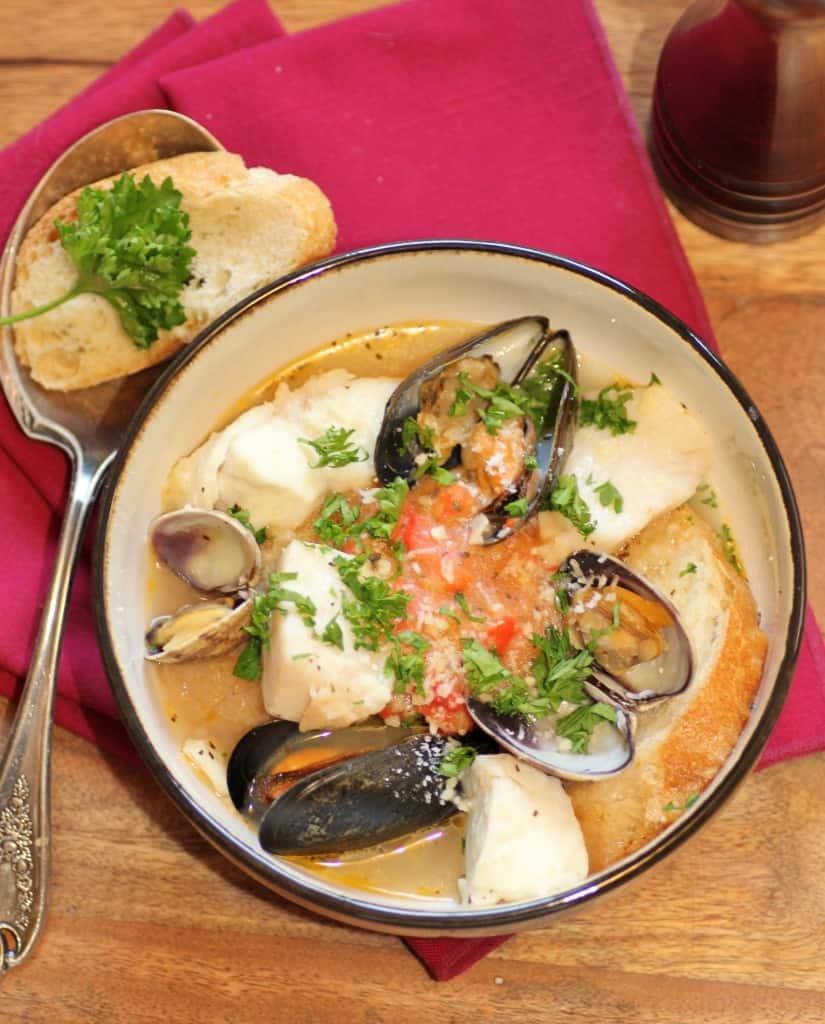 Julia Child's Bouillabaise in a bowl with a spoon and slice of French bread