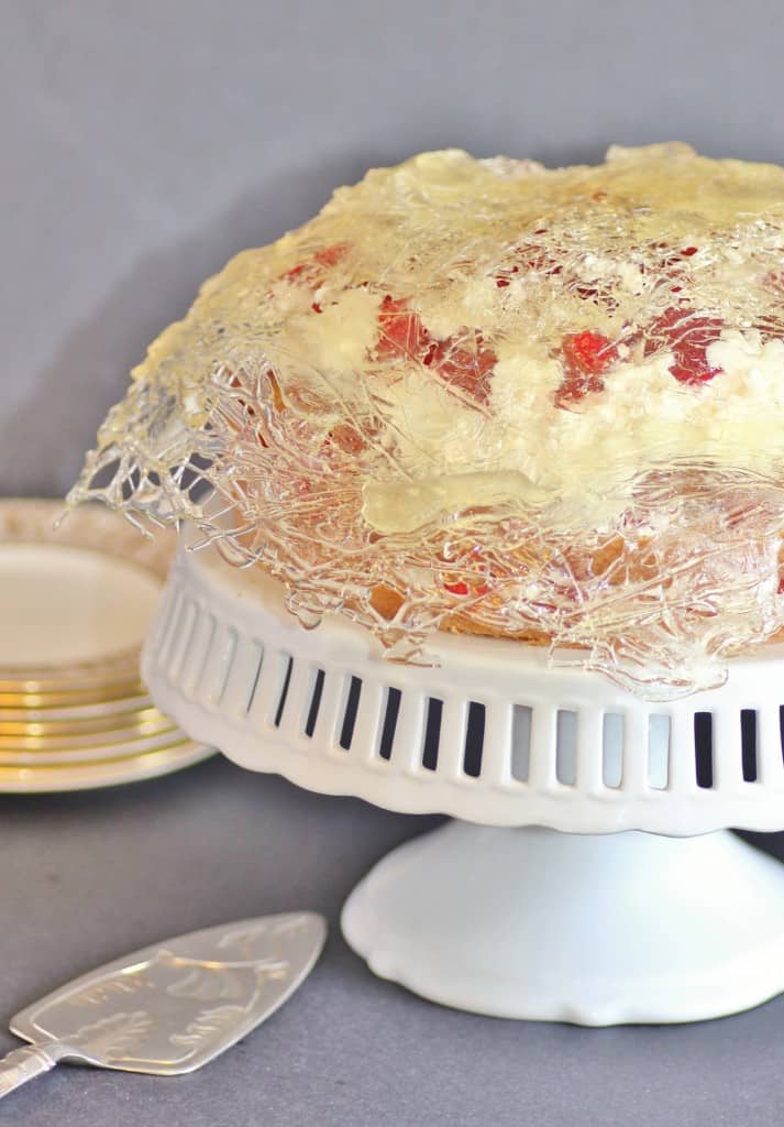 Gateau in a Cage on a white cake stand with a cake serving spatula