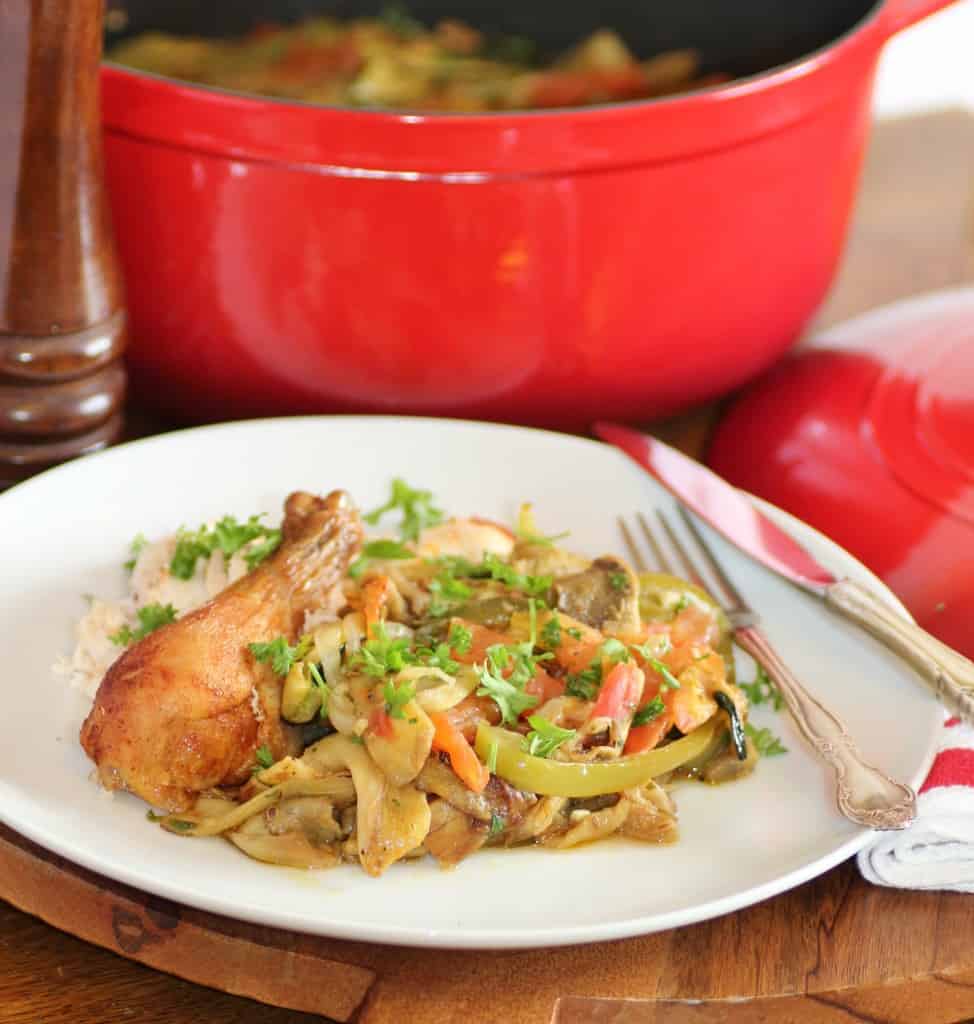 Julia Child's Ratatouille with a chicken drumstick on a white plate with a knife and fork