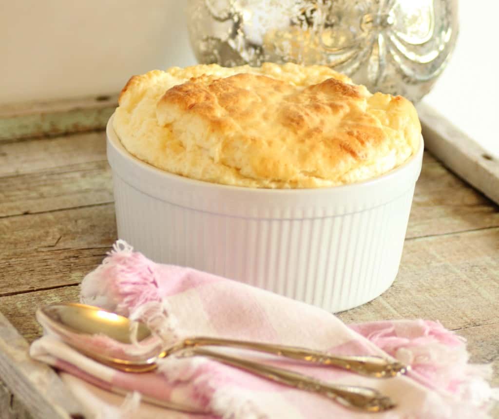 Julia Child's Lobster Cheese Souffle in a white casserole dish on a wooden board