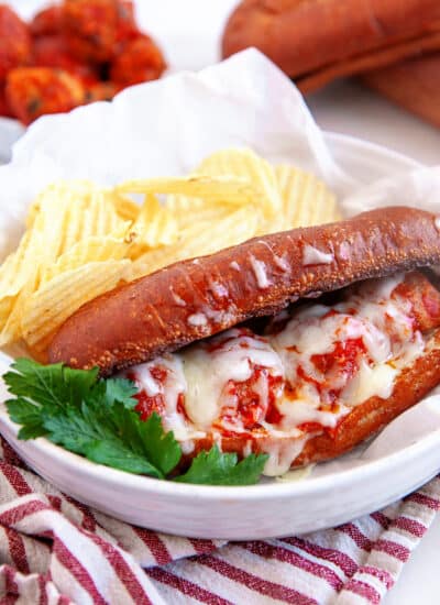 Meatball sub on a plate with ripple chips.