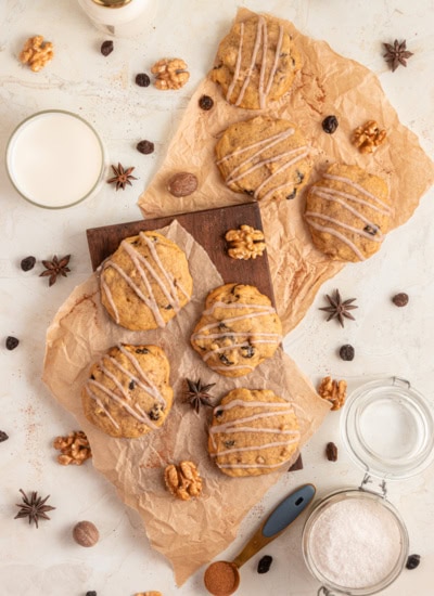 Overhead shot of pumpkin cookies on parchment paper with spices and walnuts scattered around.