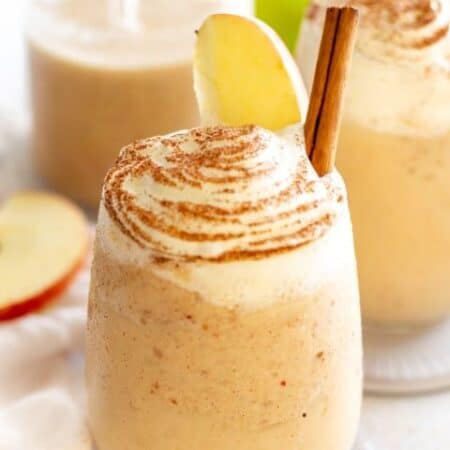 Apple Pie Smoothie in a glass with whipped cream and a cinnamon stick