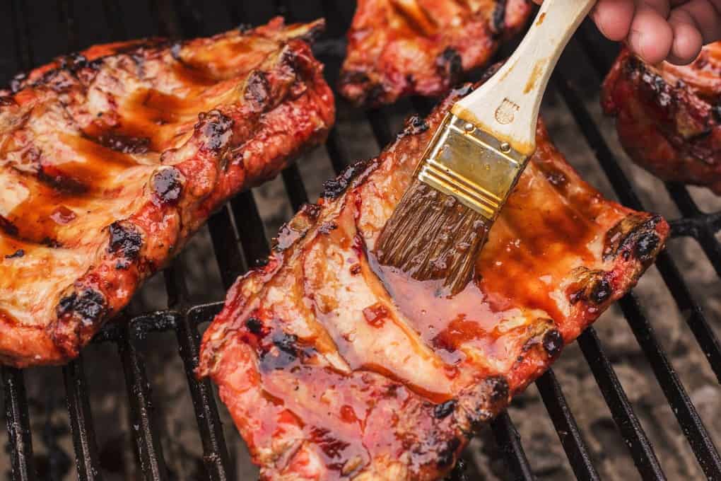 Ribs on the BBQ being basted with grill glaze