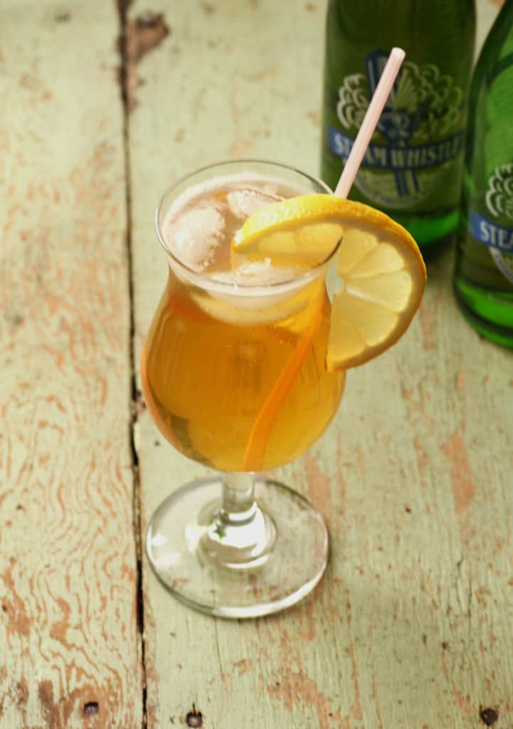 lemon whistle cocktail with a lemon slice for garnish on a wooden board