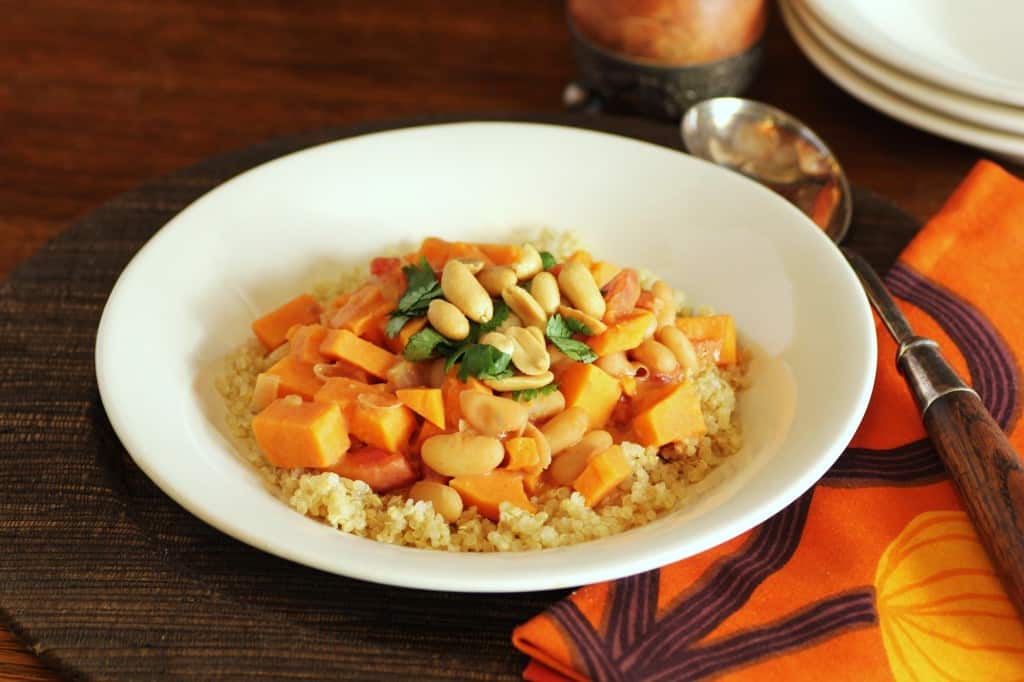 African Peanut Stew served over couscous in a white bowl with a spoon