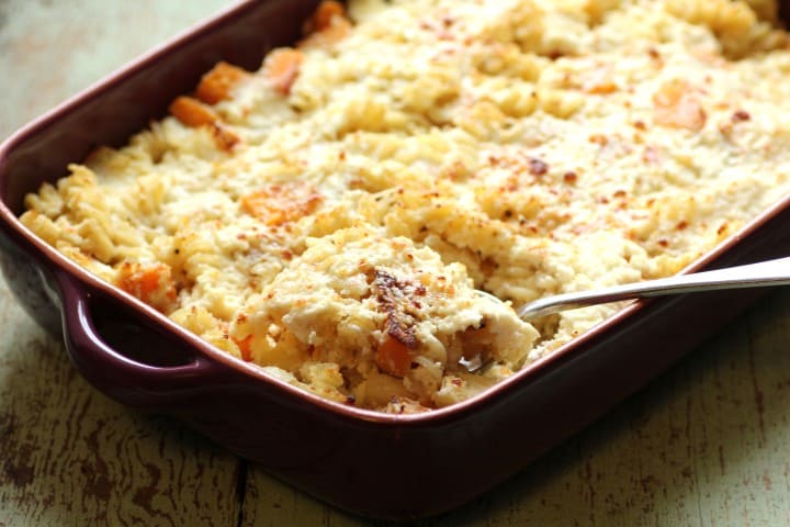 Baked Roasted Squash, Ricotta and Fusilli in a red casserole dish with a serving spoon
