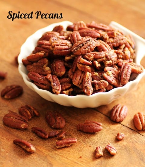 Spiced Pecans in a white bowl ona wooden board