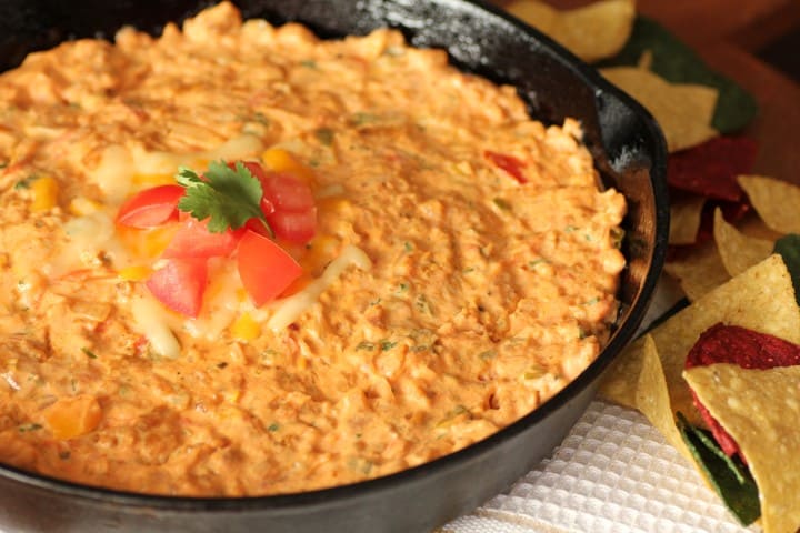 Chorizo Cheese Dip in a cast Iron Skillet with colourful tortilla chips around the pan