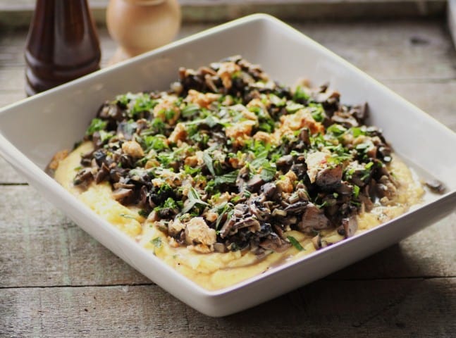Mushroom Ragout over Creamy Polenta in a white bowl on a wooden table