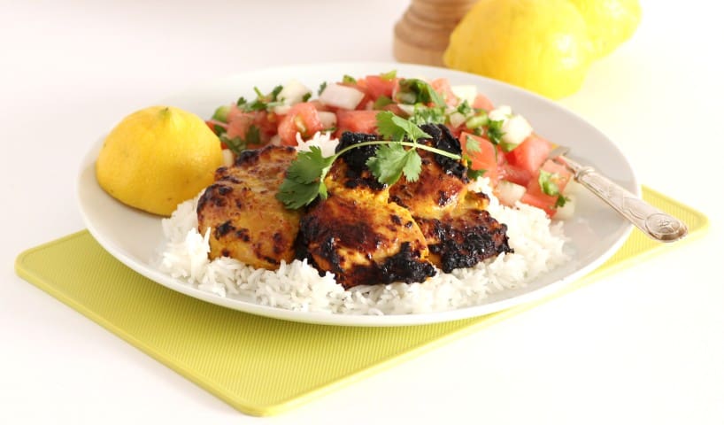 Tandoori Chicken and Tomato Onion Salad on a white plate with lemon 