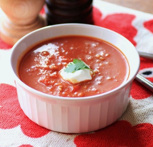 Chorizo and Roasted Red Pepper Soup in a white ramekin on a red flowered tea towel