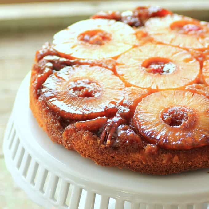 Square photo of Pineapple Upside Down Cake on a white cake stand