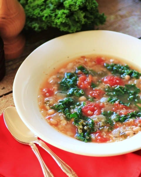 Quinoa and Kale Soup in a white bowl with a red napkin and spoons. 