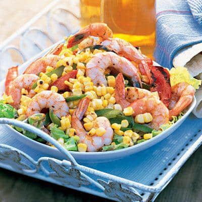 Shrimp Salad with corn and tomatoes in a white bowl on a serving tray
