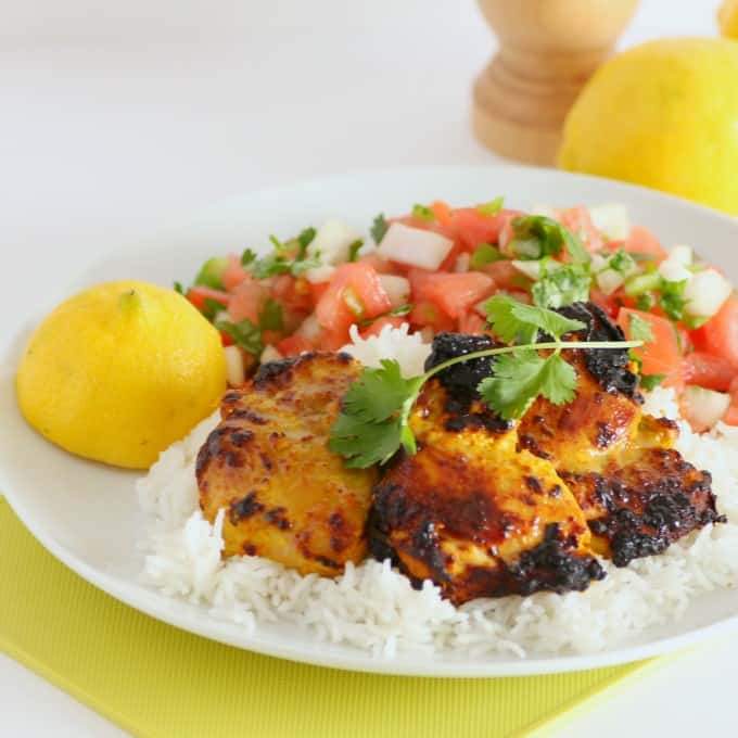 Tandoori Chicken and Tomato Onion Salad on a white plate with lemon