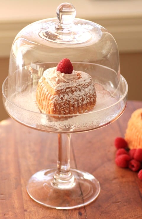 Heart Shaped White Chocolate Cakes with Raspberry Cream in a glass domed stand on a wooden board