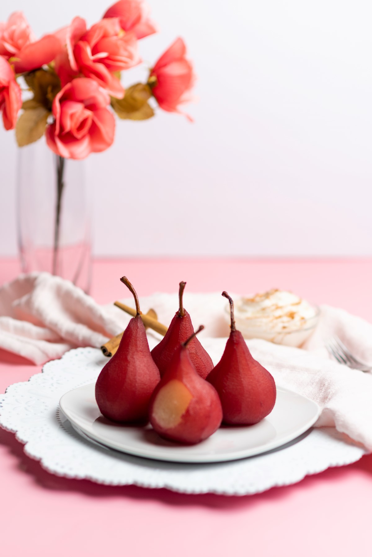 Red wine poached pears on a white plate.