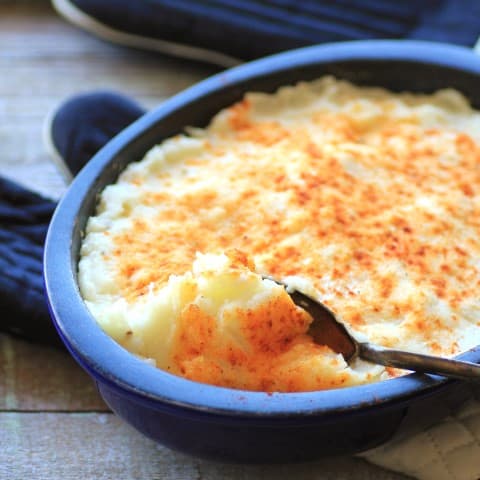 Cabbage and Potato Pie in a blue casserole dish with a serving spoon