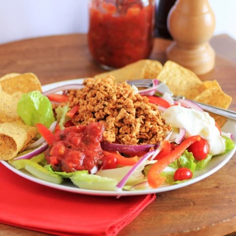Chicken Taco Salad on a white plate with tortilla chips, salsa and sour cream