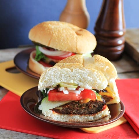 Bacon, Pickle and Cheese Stuffed Burgers cut in half on a small brown plate