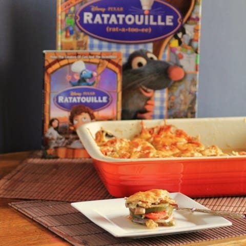 Ratatouille in a red baking dish with a spoon full on a white plate, the DVD Ratatouille in the background