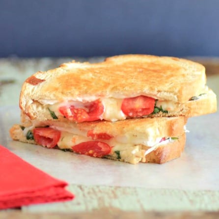 French Brie Grilled Cheese Sandwich sliced in half and stacked on wooden board