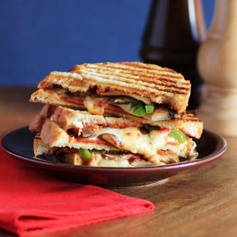 Pizza Panini sandwich cut in half and stack on a small brown plate