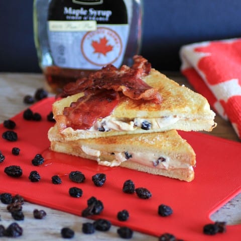 Rum and Raisin French Toast cut in half with raisins scattered around on a red cutting board