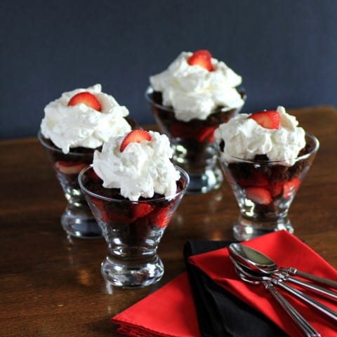 Brownie Delight  in glass serving dishes with whipped cream and a sliced strawberry on top