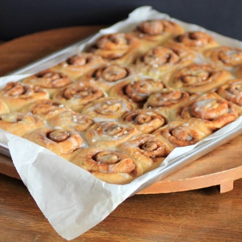 Full baking sheet tray of Cinnamon Buns on a wooden board