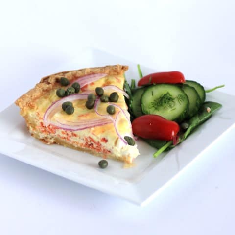 Slice of Smoked Salmon and Cream Cheese Quiche on a white plate with a green salad