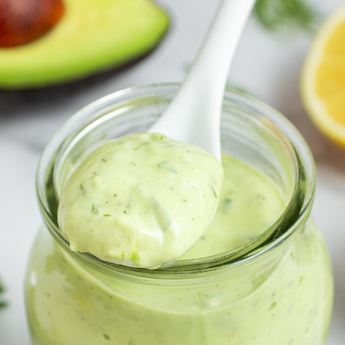 Square photo of a spoonful of avocado ranch dressing. 