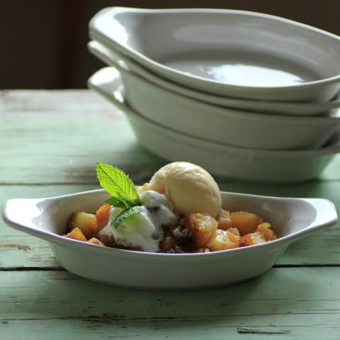 Pineapple Crisp in a oval serving dish with a scoop of ice cream on top