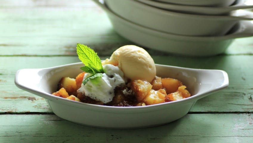 Pineapple Crisp in a oval serving dish with a scoop of ice cream on top
