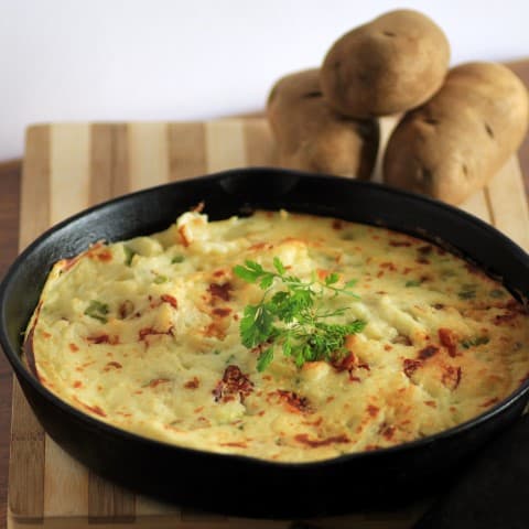 Smoked Mashed Potatoes in a cast iron frying pan on a wooden board