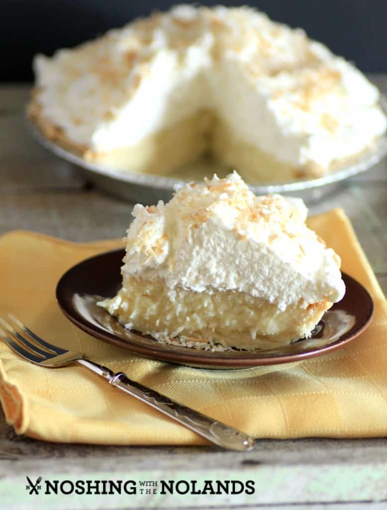 Coconut Cream Pie with a slice cut on and sitting on a brown serving plate