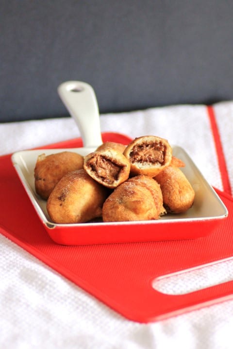 Deep Fried Mars Bars in a small red and white dish with one broken in half on top