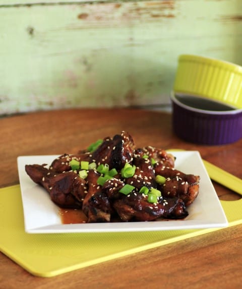 Balsamic Chicken Wings on a small white plate with Green onion and sesame seeds as garnish