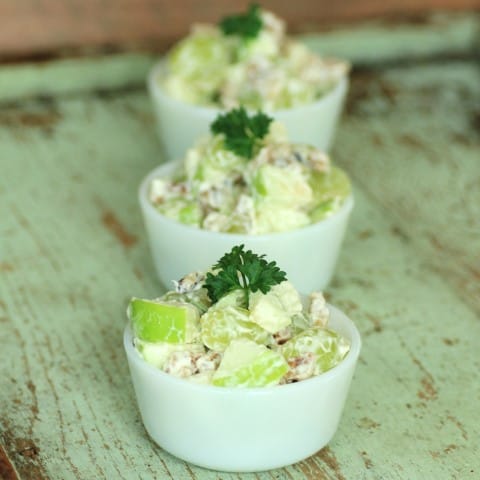 Waldorf Salad in small white bowls on a green wooden board