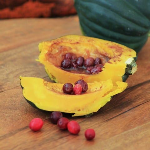 Acorn Squash with Cinnamon and Cranberries sliced on a wooden board