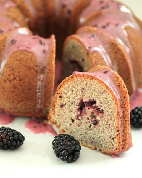 Blackberry Bundt close up of a slice cut out and blackberries.