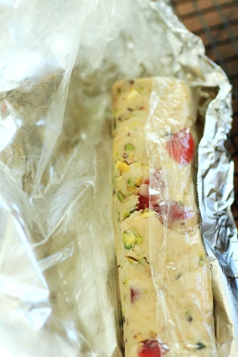 Cherry Pistachio Ice Box Cookies in a log wrapped in plastic wrap and foil